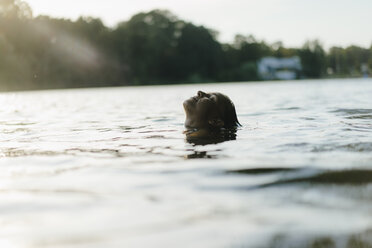 Frau schwimmt in einem See bei Sonnenuntergang - KNSF05168