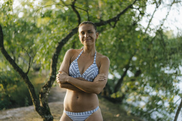 Portrait of smiling woman wearing a bikini at a lake - KNSF05176