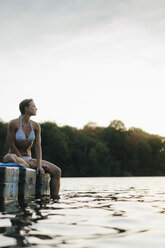 Frau im Bikini sitzt auf einem Schwimmer am See - KNSF05194
