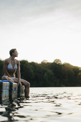 Woman wearing a bikini sitting on a float at a lake - KNSF05194