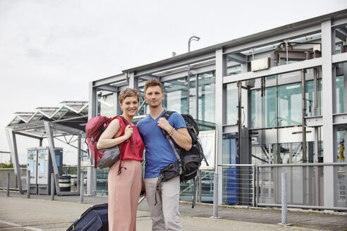 Porträt eines lächelnden Paares vor dem Flughafen - RHF02210