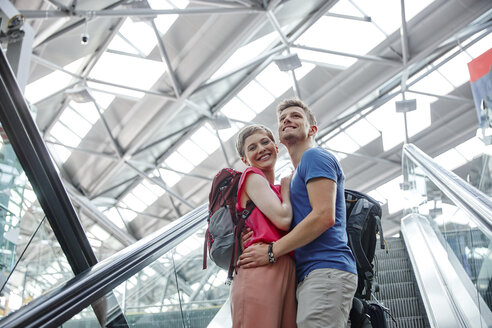 Glückliches Paar auf Rolltreppe am Flughafen - RHF02221