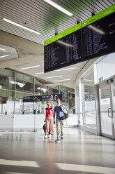Glückliches Paar auf dem Flughafen mit winkender Frau - RHF02246