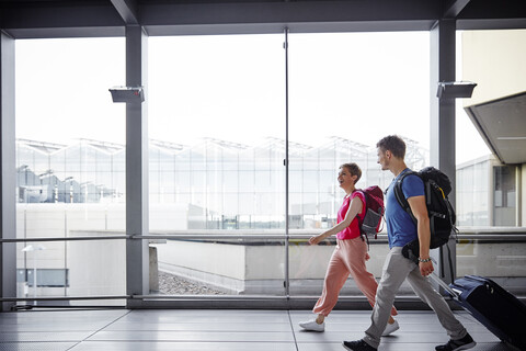 Lächelndes Paar beim Spaziergang auf dem Flughafen, lizenzfreies Stockfoto