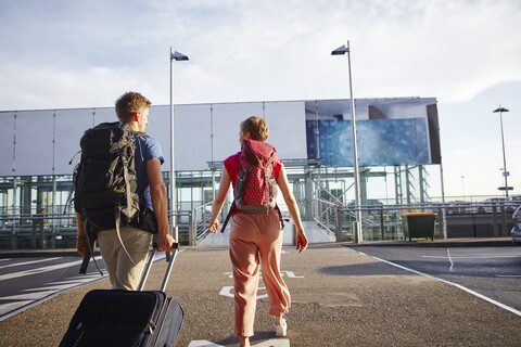 Rückansicht eines Paares, das vor dem Flughafen spazieren geht, lizenzfreies Stockfoto