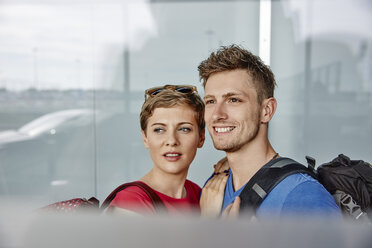 Porträt eines lächelnden Paares auf dem Flughafen mit Blick aus dem Fenster - RHF02278