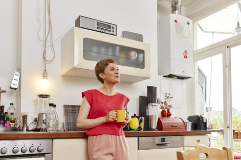 Lächelnde Frau bei einer Kaffeepause in der Küche - RHF02297