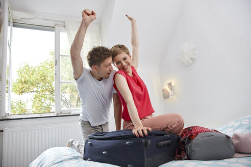 Happy couple with suitcase for summer vacation on bed - RHF02312