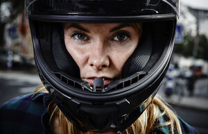 Porträt einer selbstbewussten jungen Frau mit Motorradhelm - RHF02318