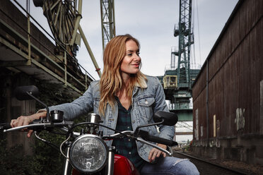 Porträt einer lächelnden jungen Frau auf einem Motorrad - RHF02331
