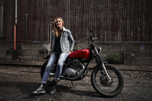 Portrait of confident young woman with motorcycle - RHF02336