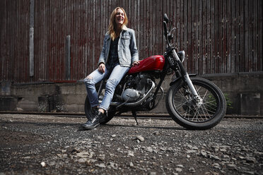 Laughing young woman with motorcycle - RHF02337