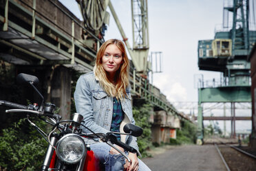 Porträt einer selbstbewussten jungen Frau auf einem Motorrad - RHF02341
