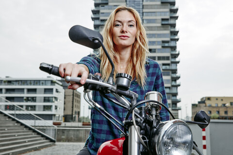 Porträt einer selbstbewussten jungen Frau auf einem Motorrad, lizenzfreies Stockfoto