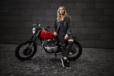 Porträt einer selbstbewussten jungen Frau mit Motorrad - RHF02354