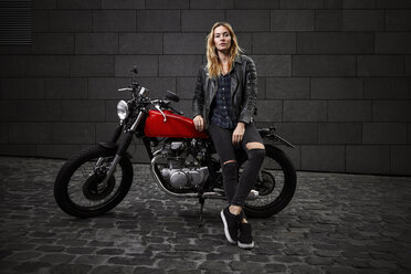 Portrait of confident young woman with motorcycle - RHF02354