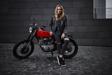 Porträt einer selbstbewussten jungen Frau mit Motorrad - RHF02356