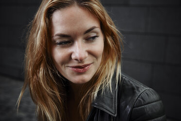 Portrait of smiling young woman wearing biker jacket - RHF02360