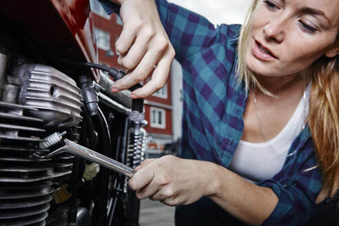 Junge Frau arbeitet an einem Motorrad - RHF02372