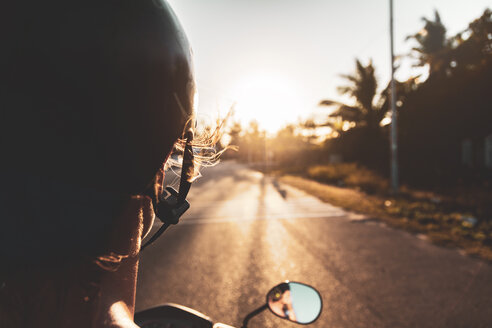Vietnam, Mui Ne, junge Frau fährt Motorroller bei Sonnenuntergang - MMAF00678