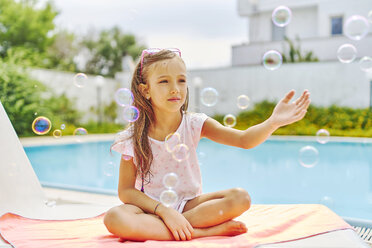 Girl playing with soap bubbles at the poolside - DIKF00303