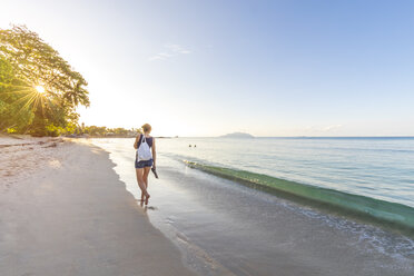 Seychelles, Mahe, Beau Vallon Beach, woman walking at the beach at sunset - MMAF00679