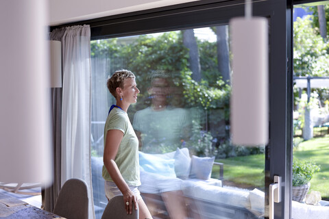 Frau schaut aus dem Fenster, lizenzfreies Stockfoto