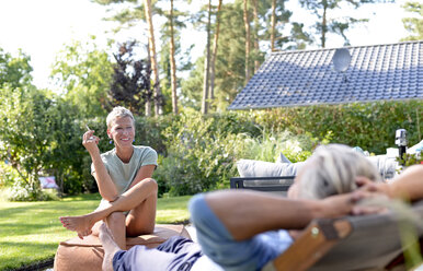 Porträt einer rauchenden Frau im Gespräch mit ihrem Partner im Garten - BFRF01913