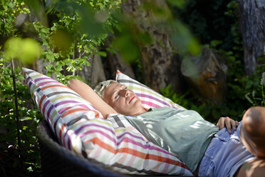 Woman relaxing on big cushion in the garden - BFRF01919