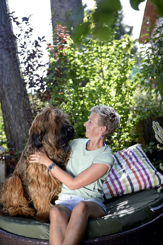 Lächelnde Frau mit ihrem Hund im Garten, lizenzfreies Stockfoto