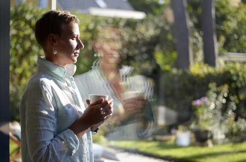 Nachdenkliche Frau mit einer Tasse Kaffee und Blick aus dem Fenster - BFRF01934