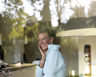 Porträt einer lachenden Frau, die aus dem Fenster schaut - BFRF01935