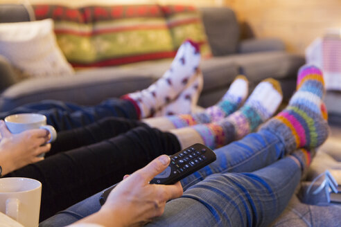 Familie in bunten Socken, die sich im Wohnzimmer vor dem Fernseher entspannen - HOXF03954