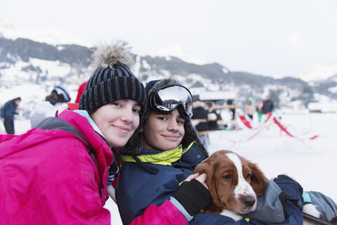 Portrait Bruder und Schwester mit Hund auf der Skipiste, lizenzfreies Stockfoto
