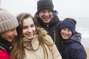 Schneefall über glücklicher Familie in warmer Kleidung - HOXF03973