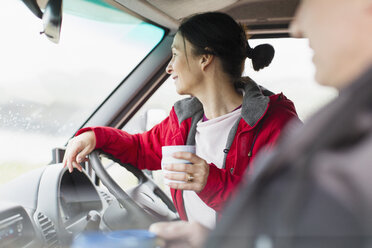 Frau mit Kaffee am Steuer eines Wohnmobils - HOXF03974