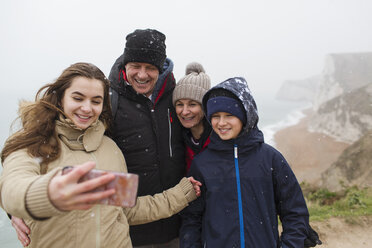Schneefall über einer Familie, die ein Selfie mit einem Fotohandy macht - HOXF03982