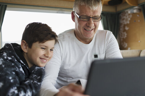 Father and son using digital tablet in motor home - HOXF03991