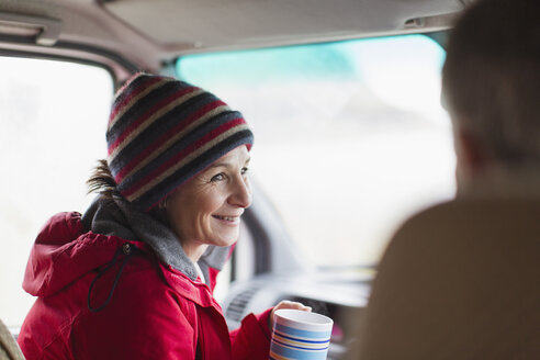 Lächelnde Frau trinkt Kaffee im Wohnmobil - HOXF03996