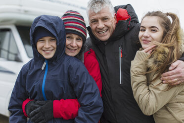 Porträt liebevolle glückliche Familie in warmer Kleidung vor Wohnmobil - HOXF03998