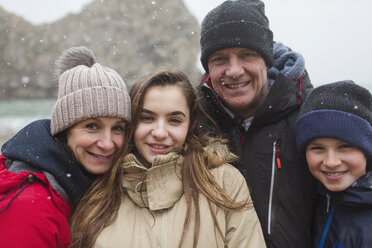 Schnee fällt über eine lächelnde Familie, die in warmer Kleidung posiert - HOXF03999