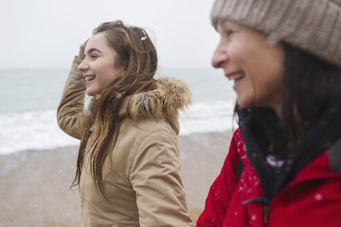 Happy mother and daughter walking on snowy beach - HOXF04001