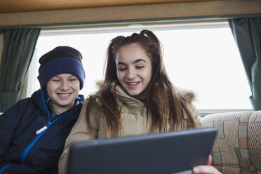 Bruder und Schwester im Teenageralter benutzen ein digitales Tablet im Wohnmobil - HOXF04013