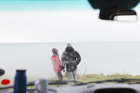 Ein Paar steht vor einem Wohnmobil auf einer Klippe mit Blick auf den Ozean - HOXF04014