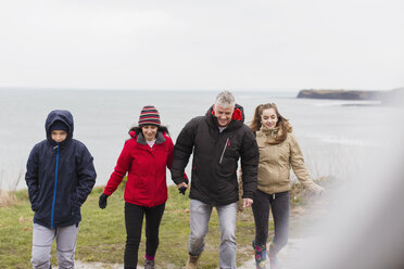 Family in warm clothing on cliff overlooking ocean - HOXF04017