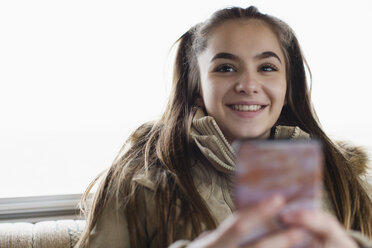 Portrait smiling, confident teenage girl texting with smart phone - HOXF04020