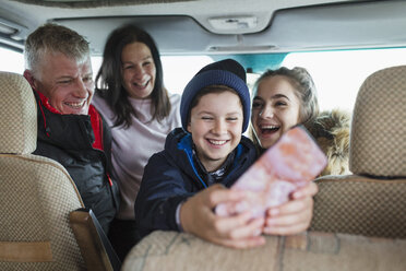 Glückliche Familie mit Smartphone im Wohnmobil - HOXF04023