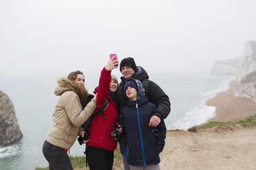 Familie mit Fotohandy macht Selfie auf einer Klippe mit Blick aufs Meer - HOXF04029