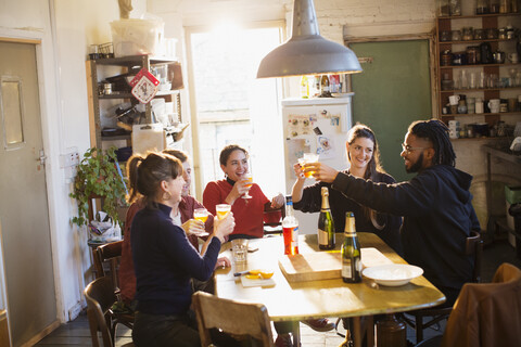Fröhliche junge erwachsene Freunde feiern, stoßen mit Cocktails in der Wohnküche an, lizenzfreies Stockfoto