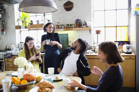 Junge erwachsene Mitbewohner und Freunde unterhalten sich am Frühstückstisch in der Wohnung, lizenzfreies Stockfoto